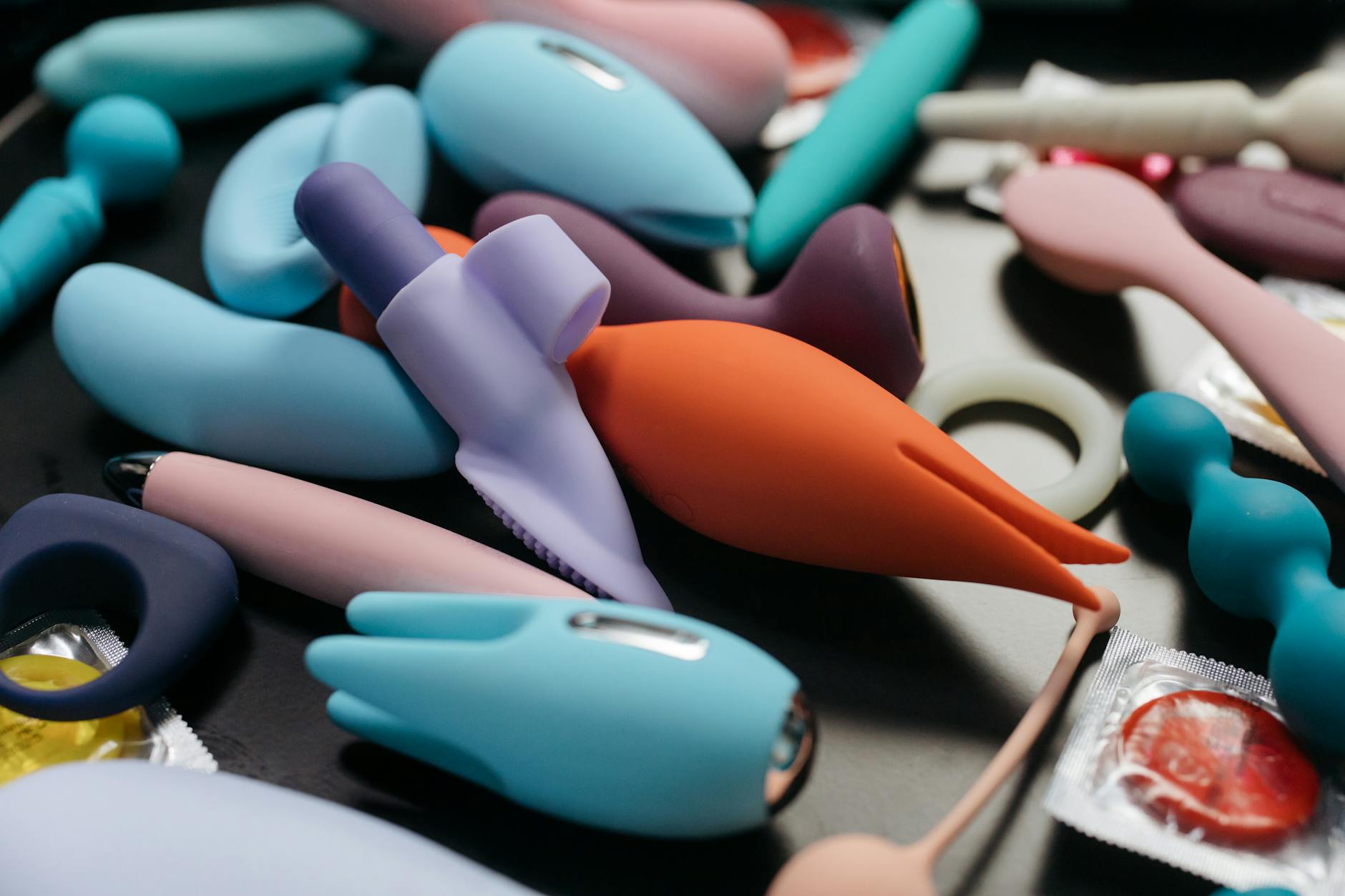 Hands exploring a collection of colorful clitoral vibrators on a table