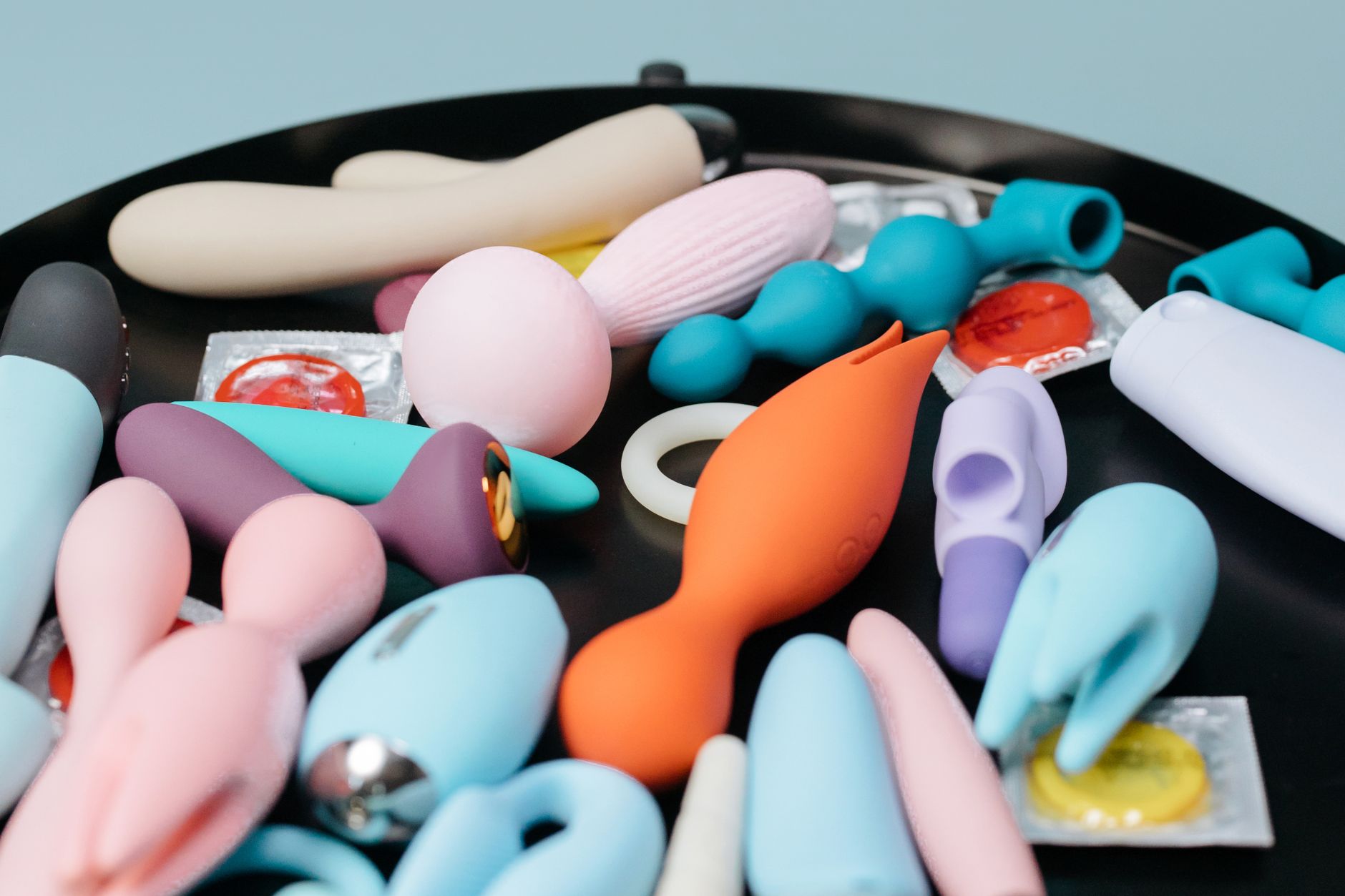 A teal-blue lemon clitoral vibrator on smooth white silk fabric