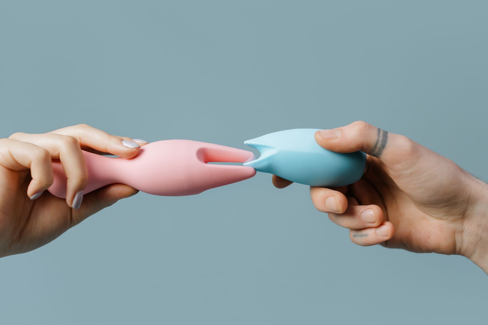 Mujer sosteniendo vibradores de silicona azul y rosa en posición contemplativa, representando exploración sensual sin prisa