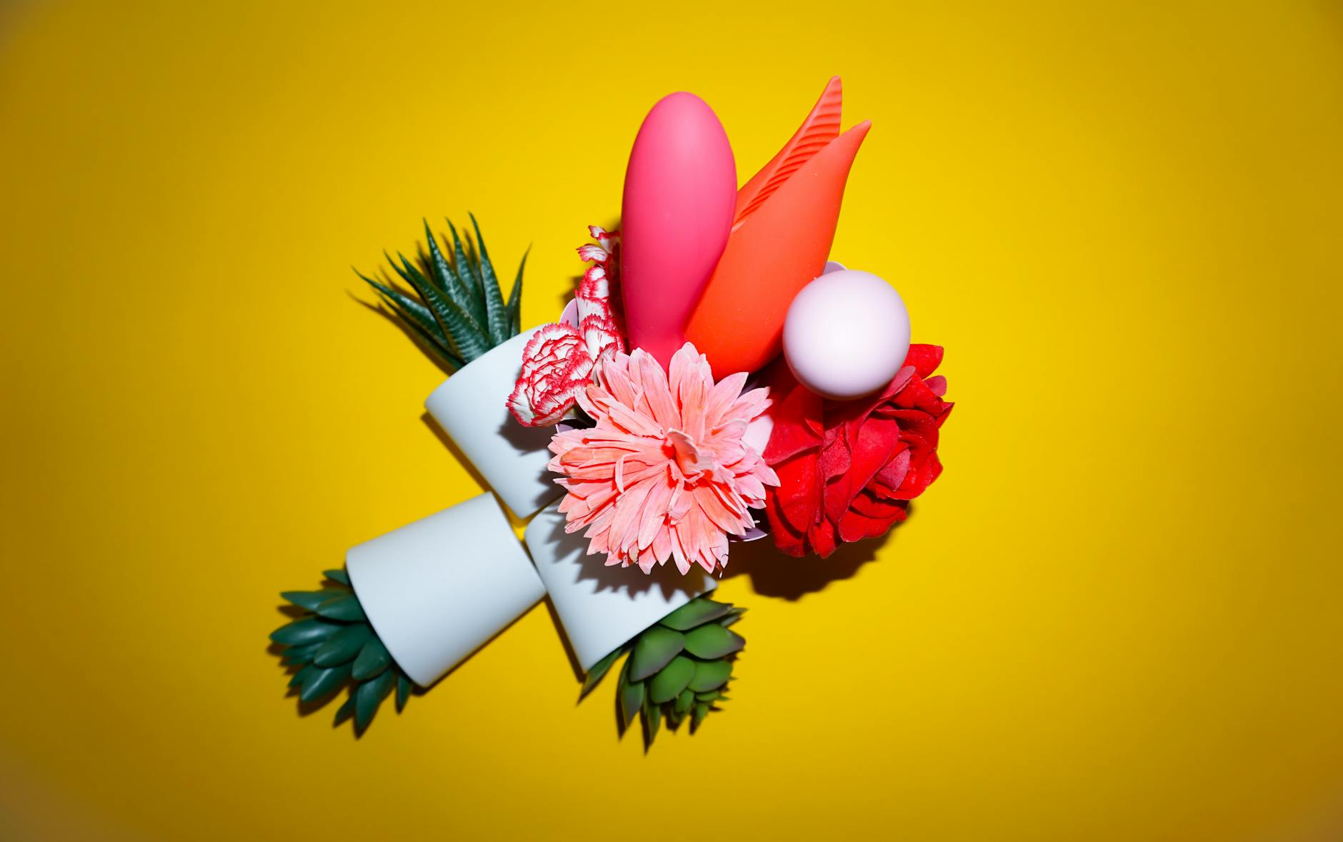A yellow silicone vibrator surrounded by fresh bananas on a bright yellow background