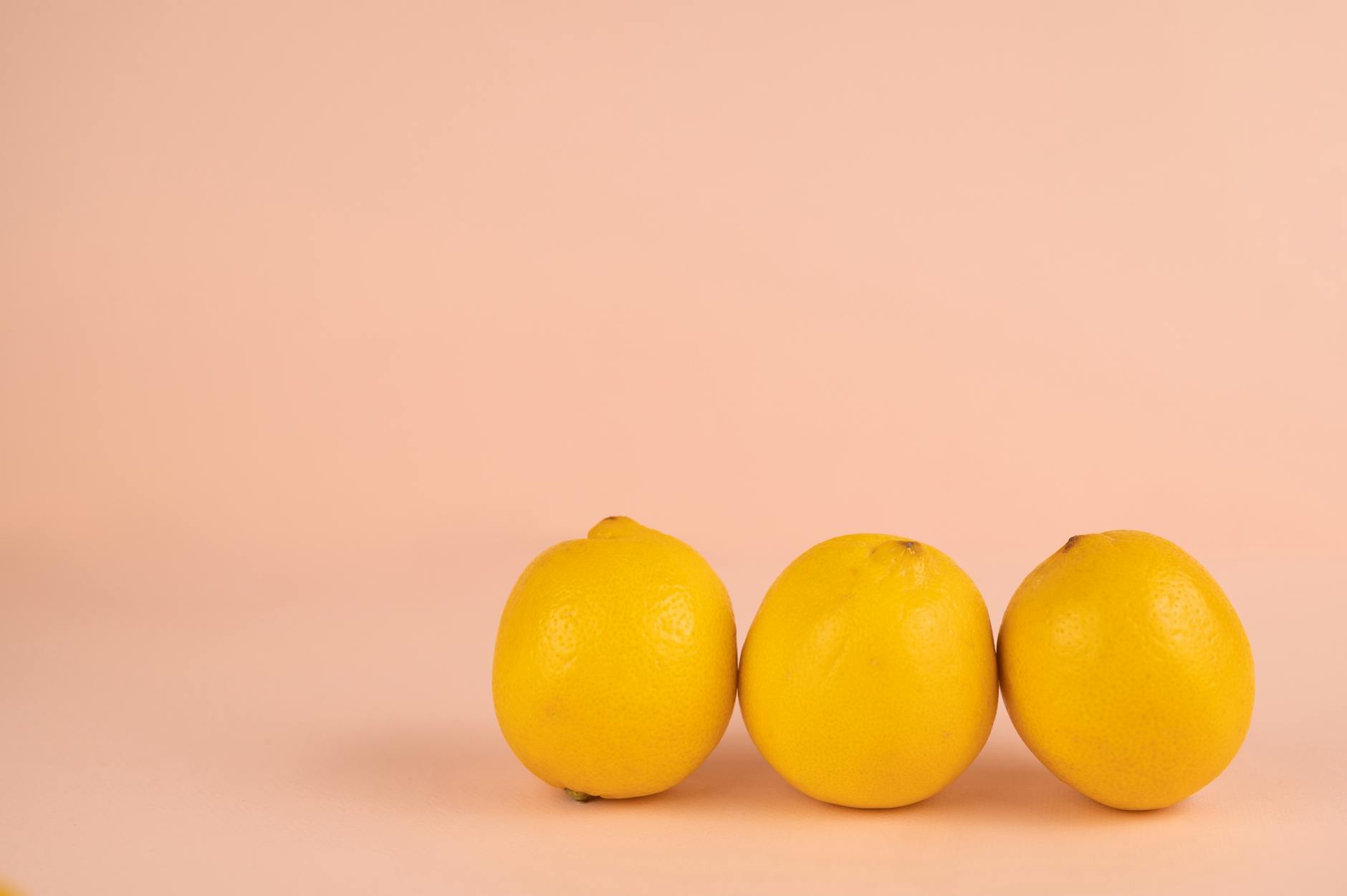 Hand holding an orange vibrator against a minimalistic purple backdrop